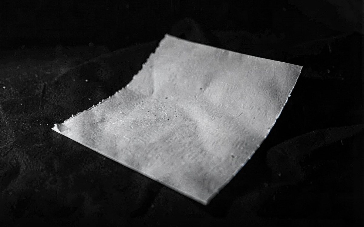 Ein einzelnes Blatt Papier hell beleuchtet auf schwarzem Grund